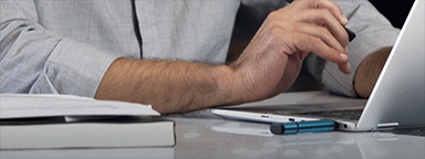 Cận cảnh một chiếc máy tính xách tay có cắm USB Kingston IronKey và bàn tay của một người đàn ông đang gõ bàn phím