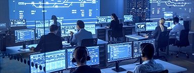 Группа по национальной безопасности работает в комнате наблюдения за компьютерами с экранами, показывающими диаграммы, графики и статистику