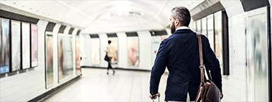 一名拿着提包和行李箱的男士在伦敦地铁行走的后视图