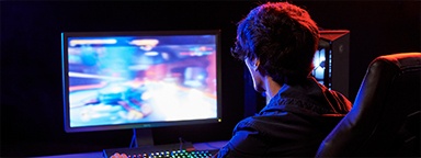 A gamer at his desk with a blurry game on his monitor