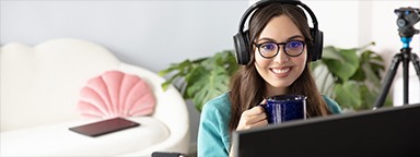 a girl holding a blue mug looking at her monitor in her home office