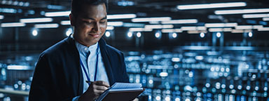 A wide shot of an employee monitoring servers in a data center, surrounded by stacks of high-tech solutions.