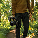 숲이 우거진 지역에서 Ben이 부착형 마운트가 달린 Canon EOS R5 카메라를 들고 있음.