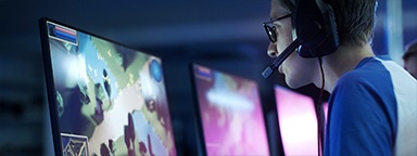 Геймер-киберспортсмен, играющий в видеоигры на своем ПК во время прямой трансляции