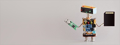 USB 플래시 드라이브 보드와 SD 메모리 카드를 들고 있는 미니어처 DIY 로봇