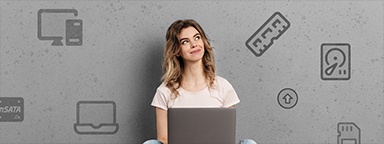 Kobieta siedząca na podłodze z laptopem i patrząca na różne symbole sprzętu komputerowego, które są zilustrowane za nią na ścianie