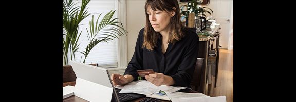 A woman looks at a tablet on a stand with many papers on the desk