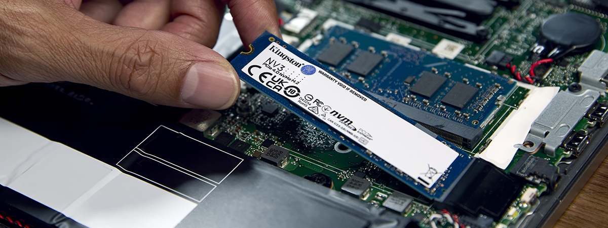Tampilan jarak dekat tangan seseorang memasang SSD Kingston NV3 NVMe ke laptop dengan modul memori Kingston yang sudah terpasang