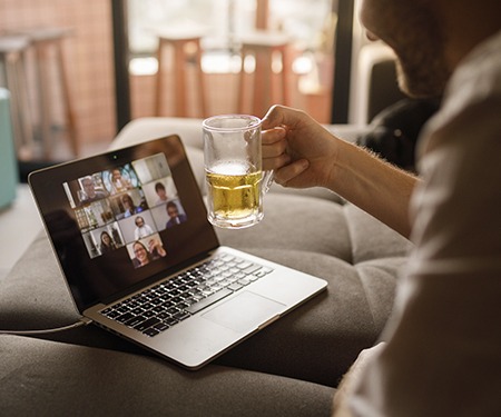 Usuario de portátil en un chat de vídeo sosteniendo una cerveza