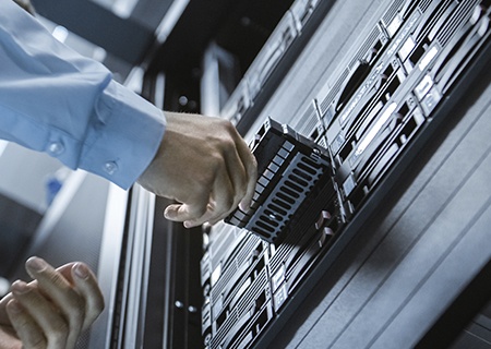 IT engineer installing storage drive into server rack