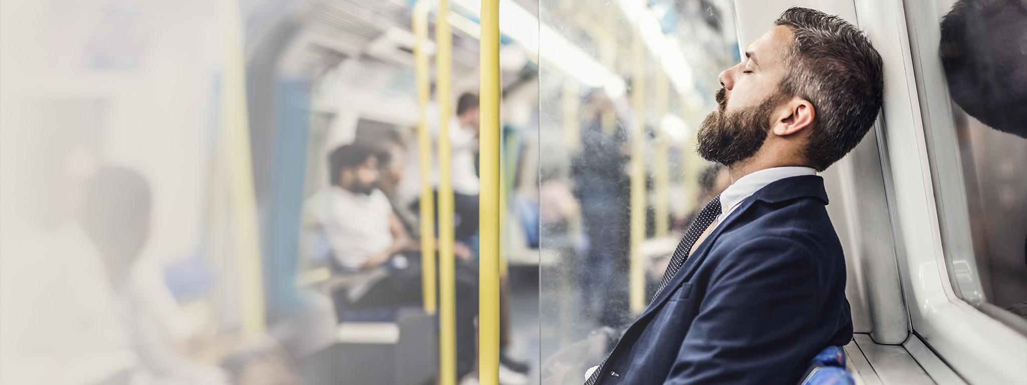 Homem de negócios dormindo e se deslocando para trabalhar em um trem subterrâneo de Londres